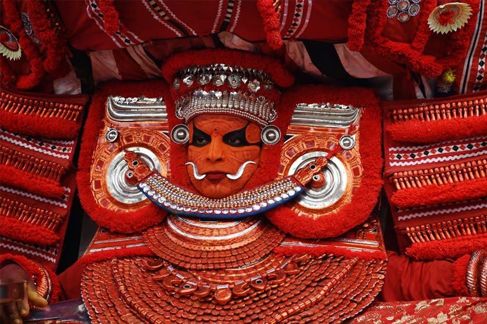 A Theyyam performer in full costume in Kannur
